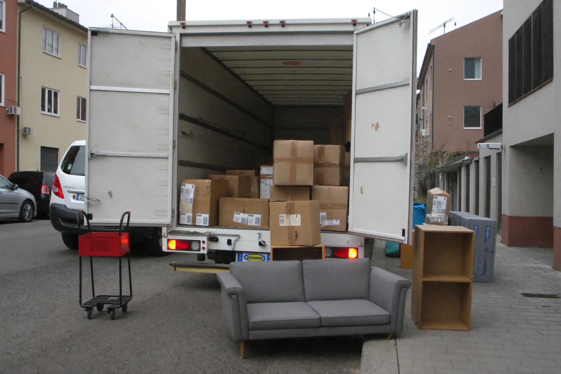 Beladener Umzugs-LKW mit Kartons und Sofa vor einem Wohnhaus